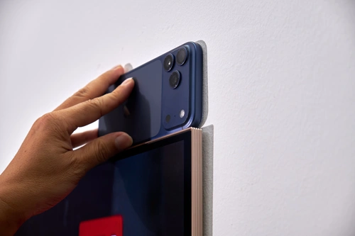 Nhờ sử dụng hộp Zero Connect Box, LG có thể dồn toàn bộ những linh kiện xử lý và kết nối qua hộp này, chỉ để lại tấm nền trên phần thân TV. Nhờ đó, hãng thu độ dày của TV xuống còn khoảng 9,9 mm, tương đương chiếc iPhone 17 Pro Max trong hình. Cộng với kích thước 83 inch và cơ chế bản lề "lõm" vào trong, LG W6 khi gắn lên tường gần như phẳng giống một bức tranh khổ lớn.